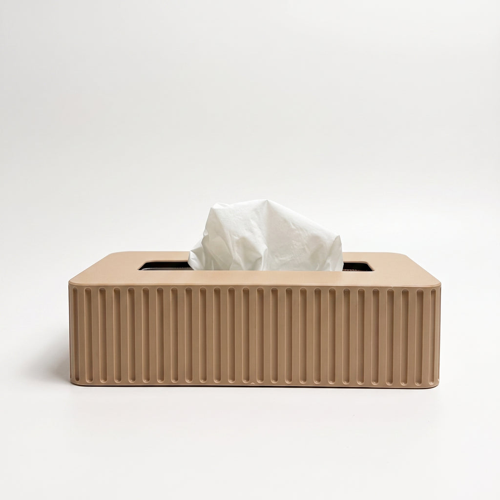 A rectangular tissue box cover in a warm beige color with vertical fluted ridges, shown with a white tissue protruding from the top on a clean white background.