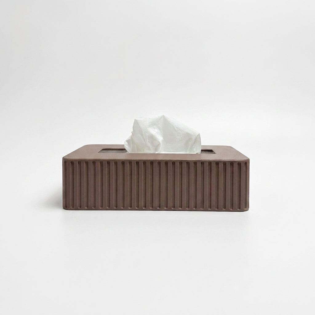 A brown rectangular tissue box cover with vertical fluted ridges, shown with a white tissue protruding from the top on a clean white background.