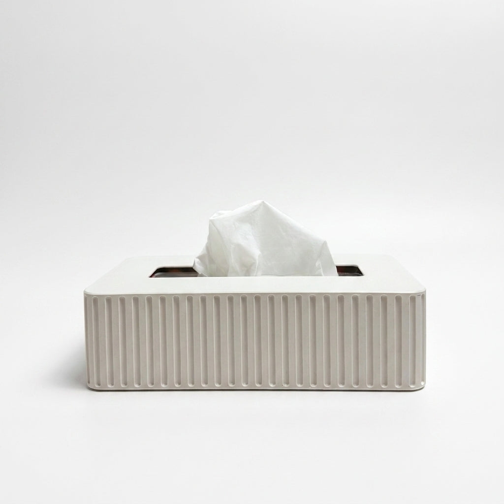 A white rectangular tissue box cover with vertical fluted ridges, shown with a white tissue protruding from the top on a clean white background.